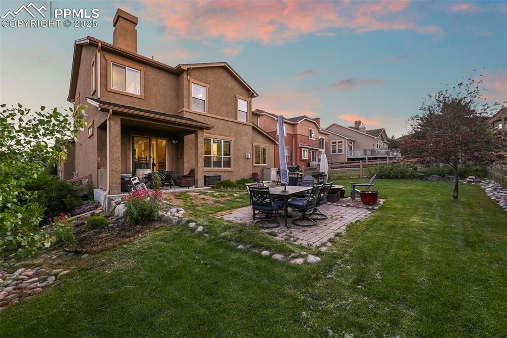 Image 49 of 50: Back of house at dusk with a patio area, a chimney, and stucco siding