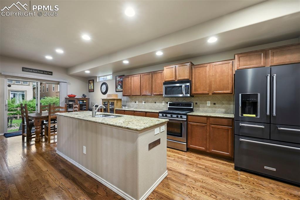 Image 9 of 50: Kitchen with stainless steel appliances, light wood finished floors, brown 