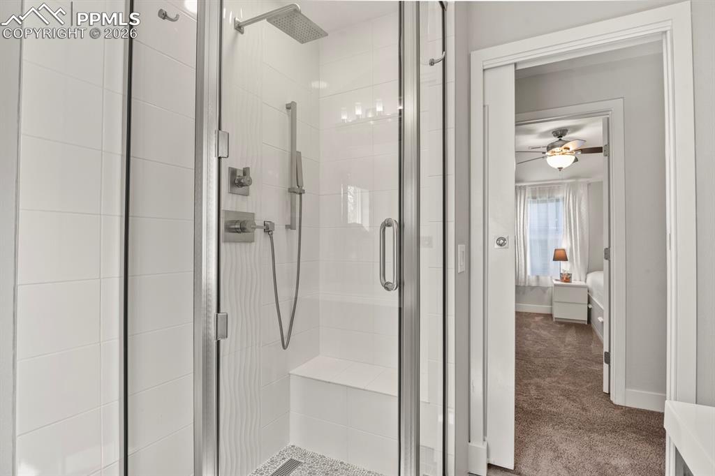 Image 31 of 50: Upper level 3/4 bathroom with pocket door and bench in the shower