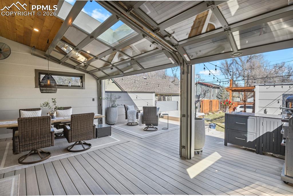 Image 35 of 50: Photo with garage doors open looking out at the backyard and extended patio
