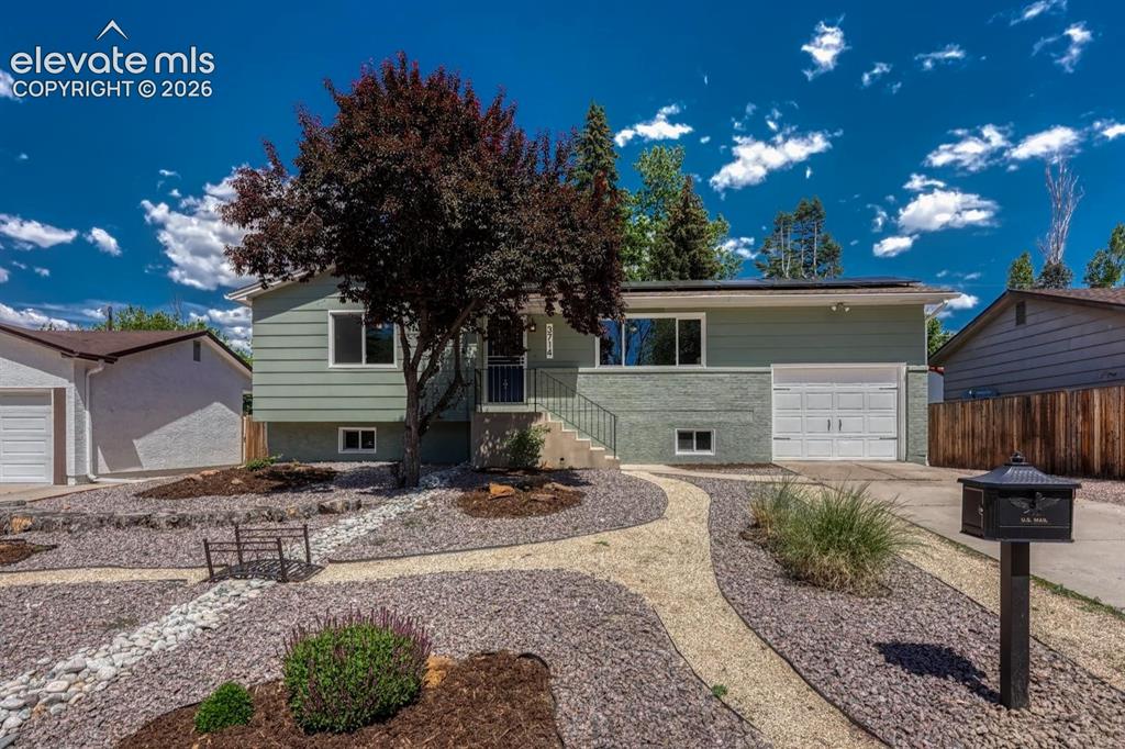 Image 1 of 29: Split-level residence featuring a light green exterior with a two-car garag