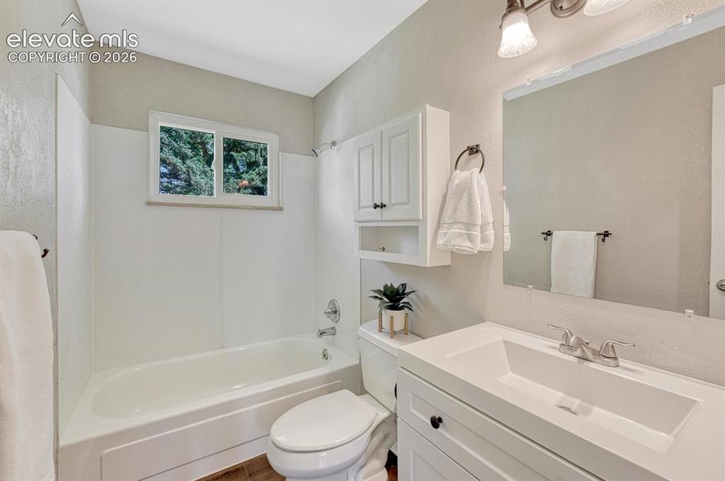 Image 11 of 29: Bathroom featuring a white vanity with integrated sink, chrome faucet, and 