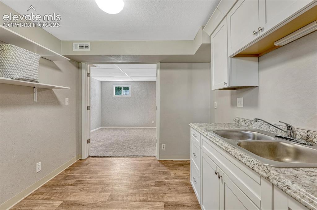 Image 17 of 29: Kitchenette featuring white cabinetry, a double basin stainless steel sink,