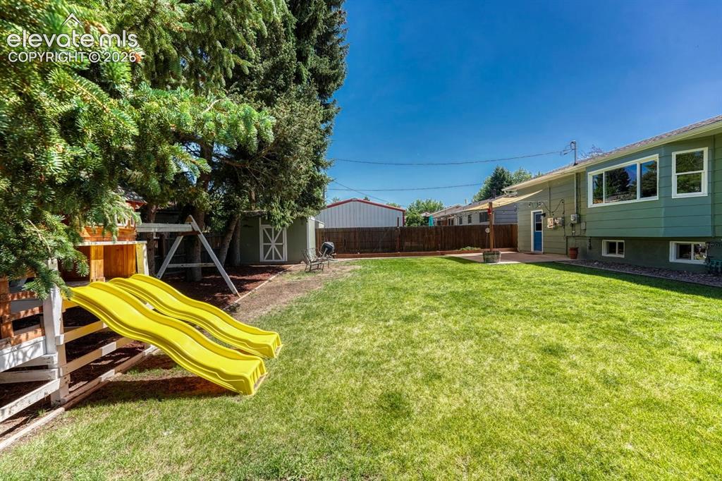 Image 2 of 29: Expansive green lawn with mature trees and a privacy fence