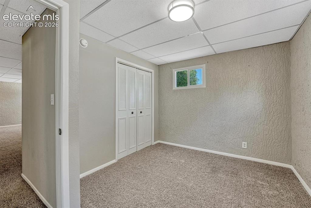 Image 20 of 29: Carpeted room featuring a white bi-fold closet, a single window, and a drop