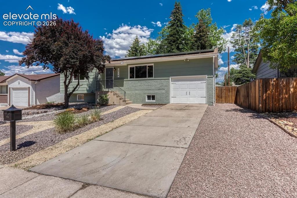Image 22 of 29: Split-level residence featuring a sage green exterior with a contrasting br
