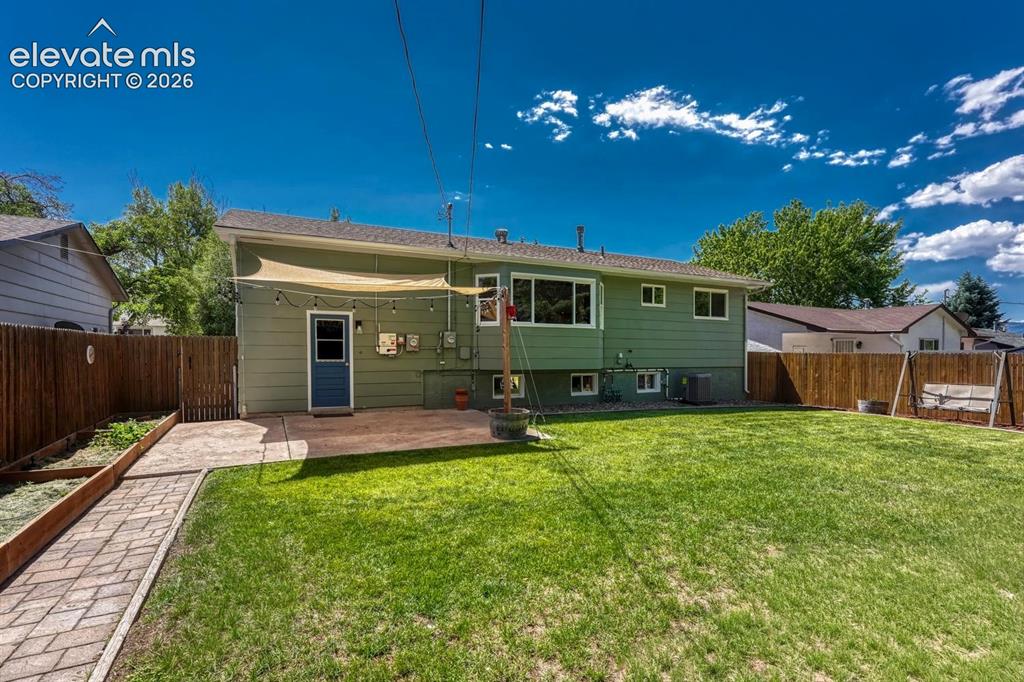 Image 23 of 29: Expansive backyard featuring a large green lawn, concrete patio, and a pave