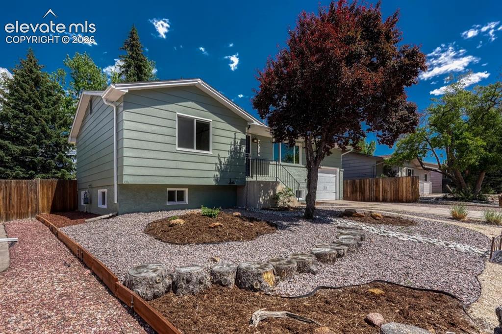 Image 24 of 29: Contemporary raised ranch residence featuring light green siding and white 