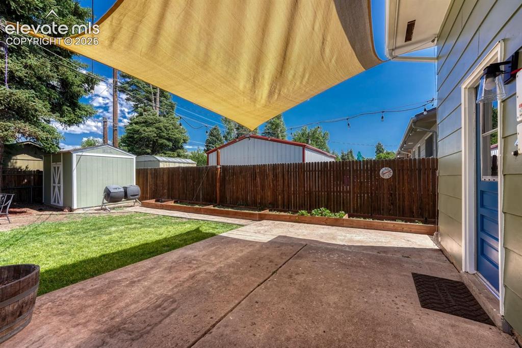 Image 26 of 29: Spacious concrete patio featuring a sun shade and string lighting