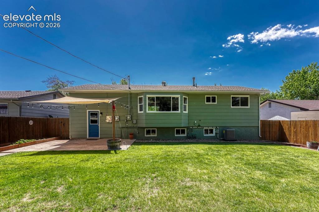 Image 29 of 29: Expansive backyard featuring a lush lawn, privacy fencing, and a patio area