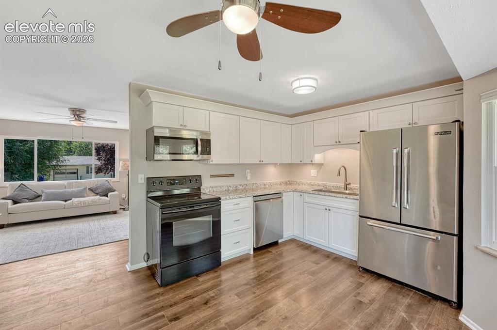 Image 4 of 29: Kitchen featuring white cabinetry, stainless steel appliances, light-toned 