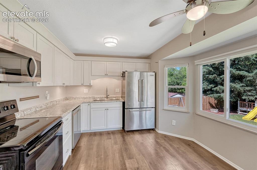 Image 5 of 29: Contemporary kitchen featuring light wood-finish flooring and white cabinet