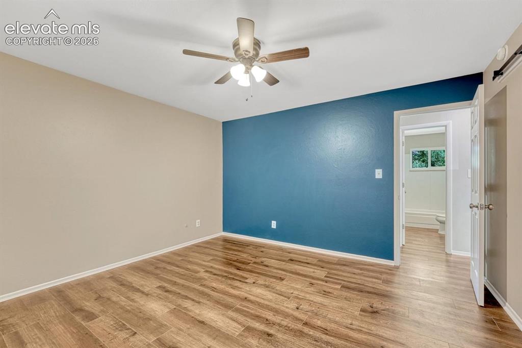 Image 8 of 29: Spacious room featuring wood-finish flooring, a ceiling fan with integrated