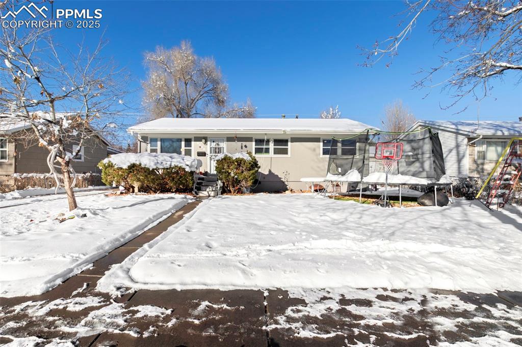 Caption: Snow covered front of property with a trampoline