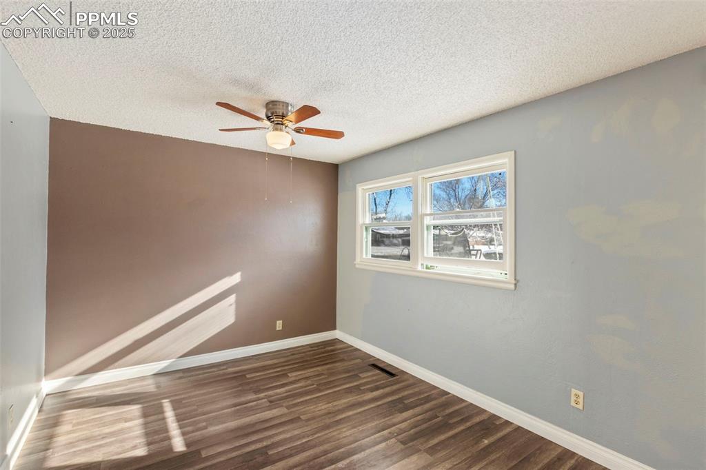 Image 14 of 25: Unfurnished room with ceiling fan, a textured ceiling, and dark wood-type f
