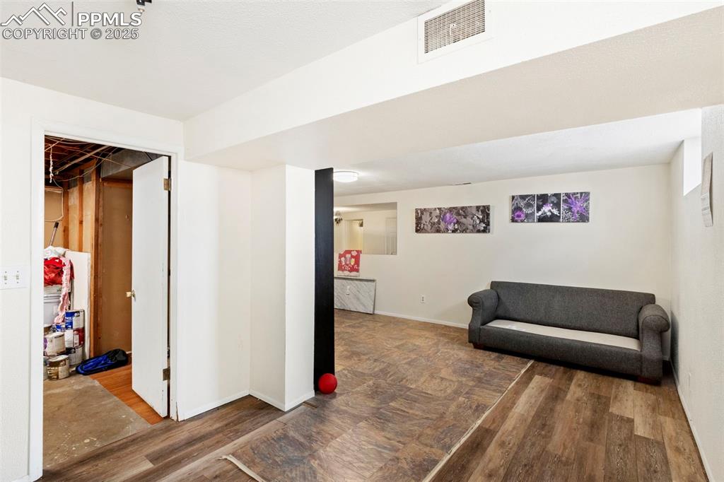 Image 16 of 25: Living area with dark wood-style flooring