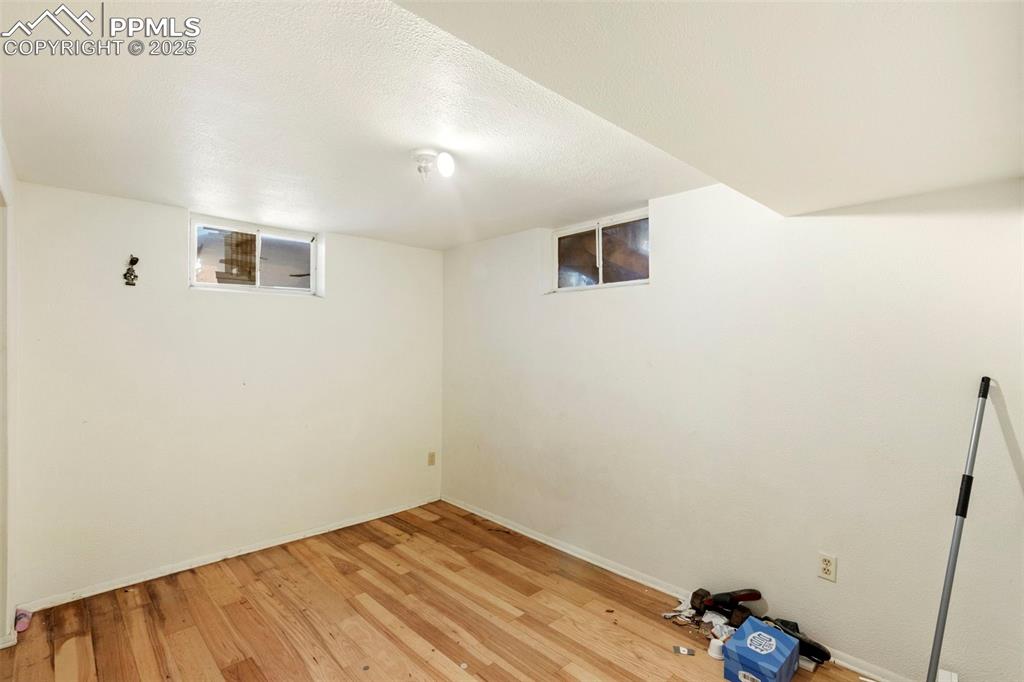 Image 20 of 25: Finished basement bedroom with a textured ceiling and light wood-style floo