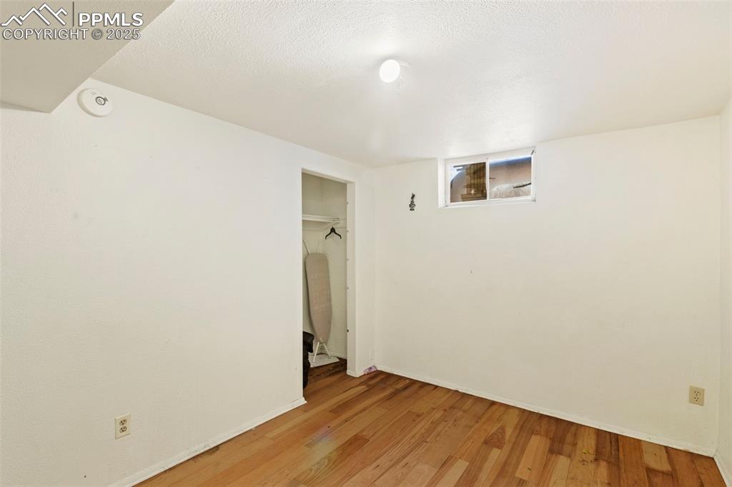 Image 21 of 25: Unfurnished bedroom featuring a textured ceiling, a closet, and light wood 