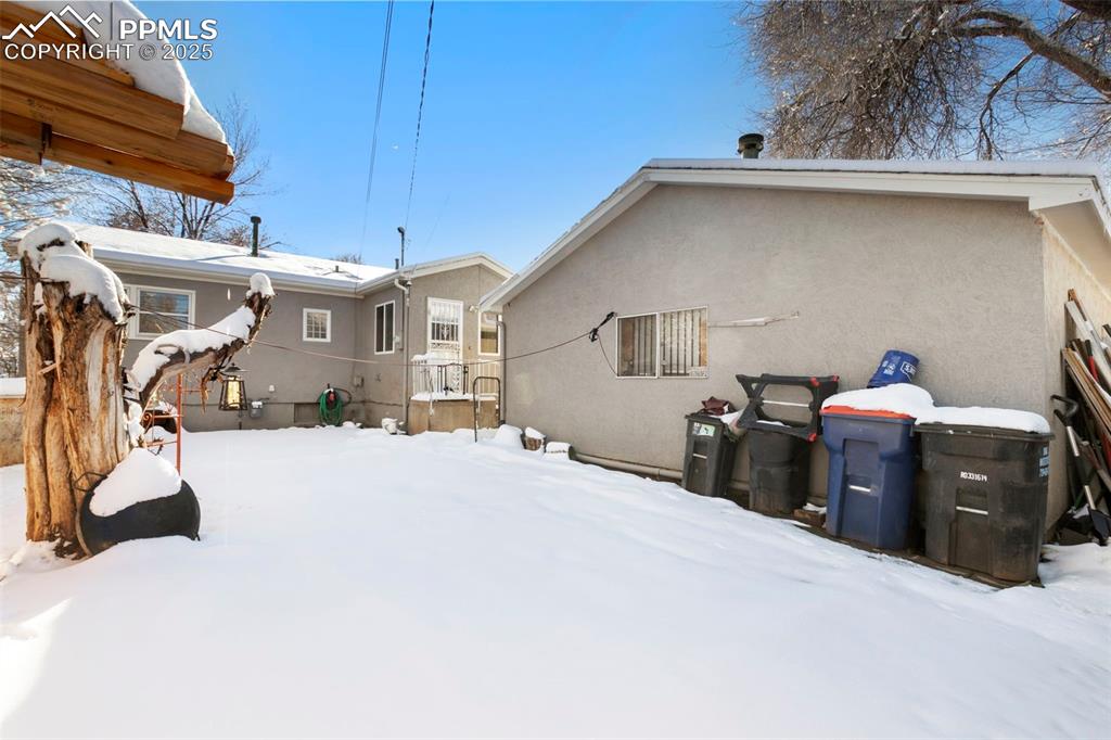 Image 24 of 25: Snow covered property with stucco siding
