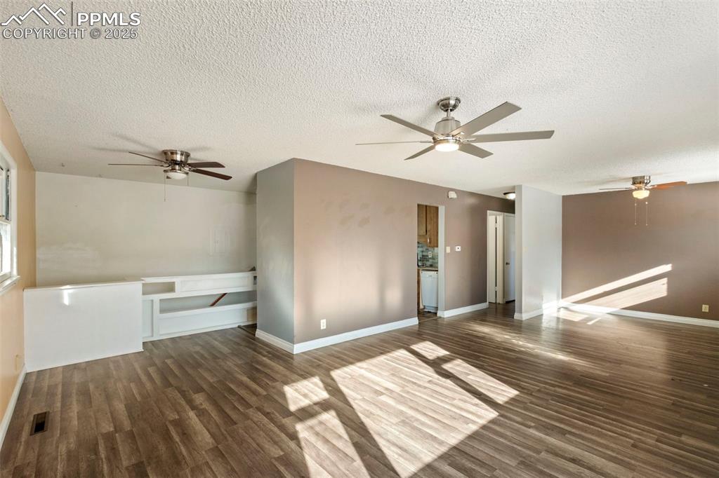 Image 5 of 25: Unfurnished living room featuring ceiling fan, dark wood-style flooring, an