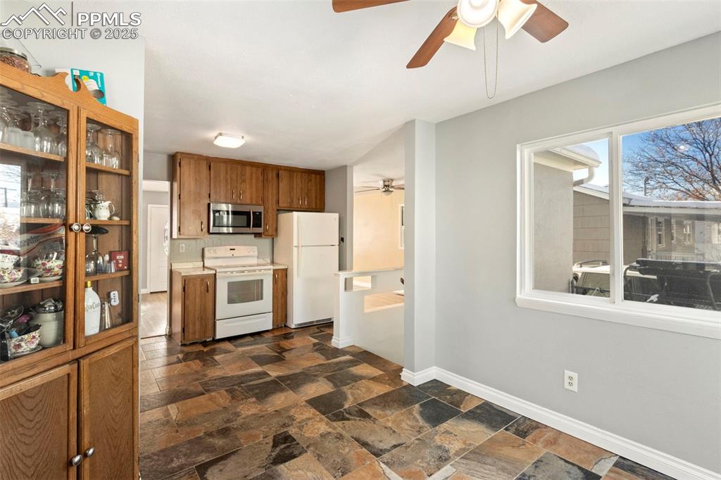 Image 7 of 25: Kitchen with brown cabinetry, white appliances, light countertops, a ceilin