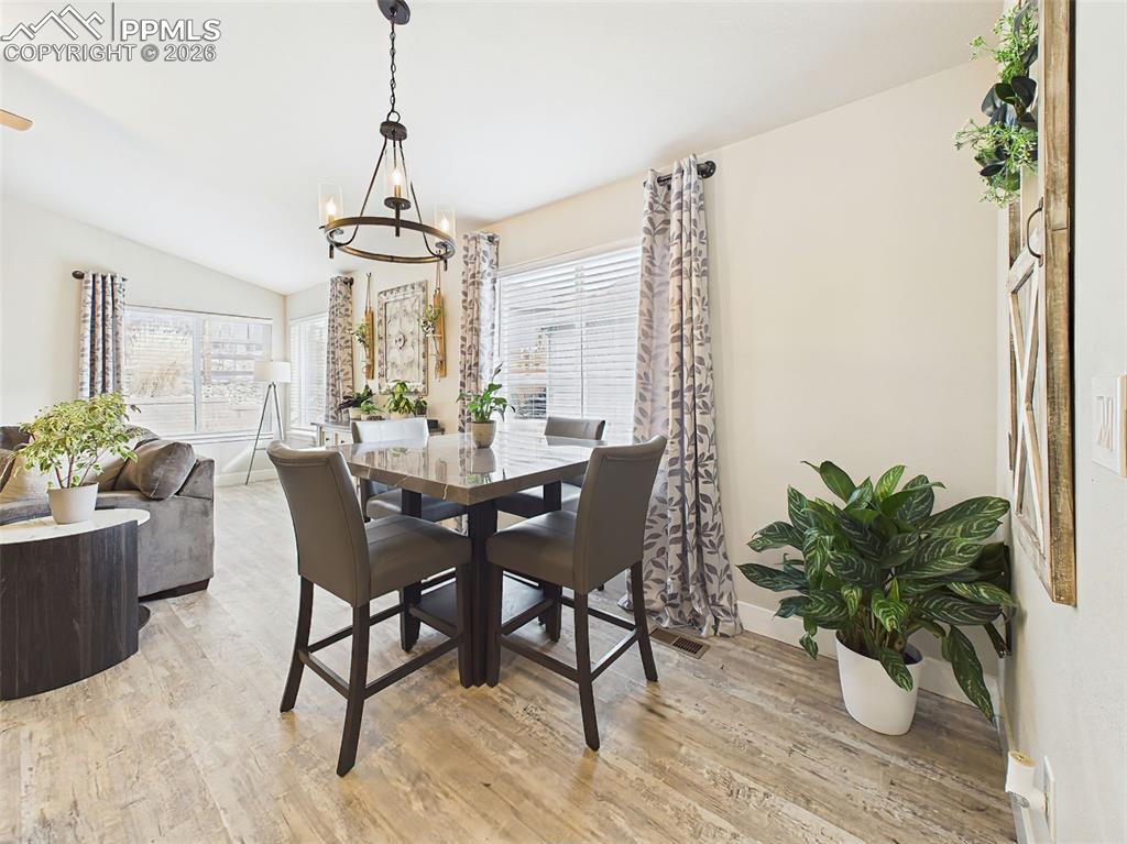 Image 12 of 50: Dining space with large windows, chandelier lighting, and easy flow to livi