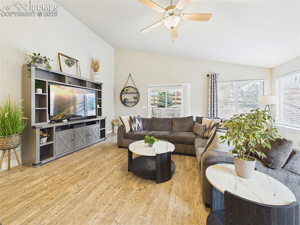 Image 14 of 50: Comfortable living room with large windows, ceiling fan, and access to back