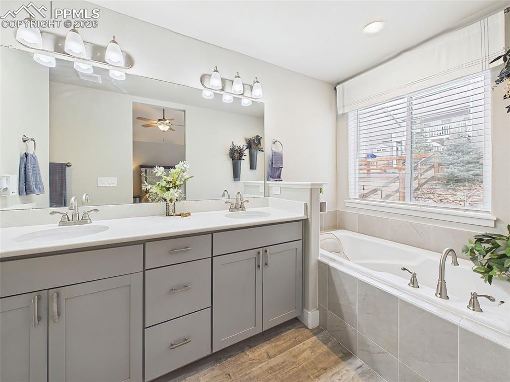 Image 18 of 50: Primary bathroom with dual vanity, large mirror, and soaking tub beside win