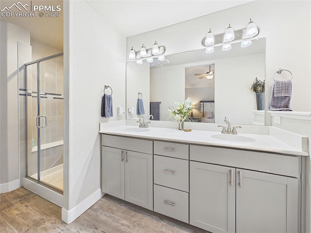 Image 19 of 50: Spacious primary bath featuring dual sinks, tile flooring, and glass-enclos