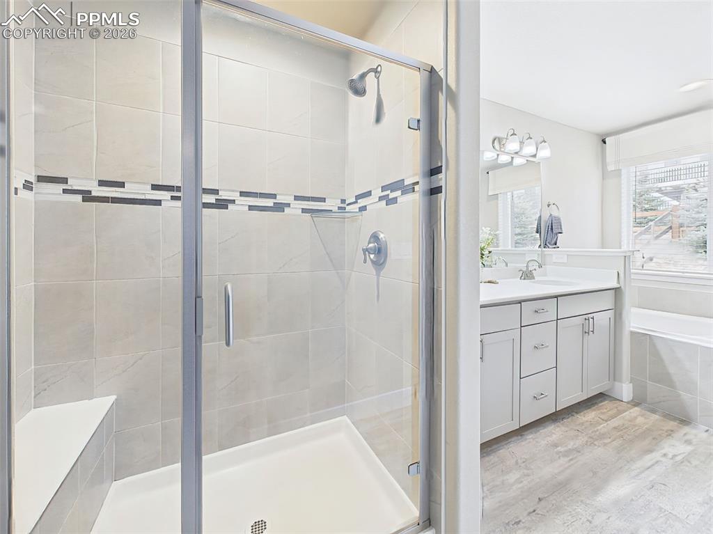 Image 20 of 50: Walk-in shower with tile surround and glass enclosure adjacent to dual vani