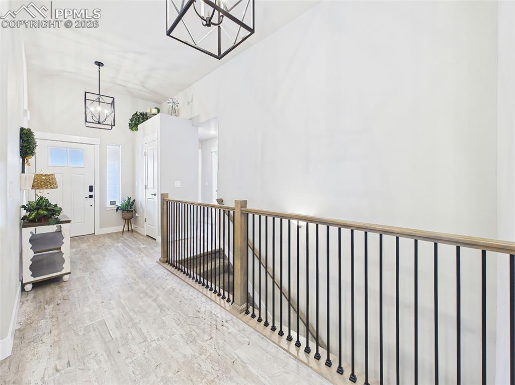 Image 23 of 50: Open upper-level enrty hallway with modern railing, vaulted ceilings, and s