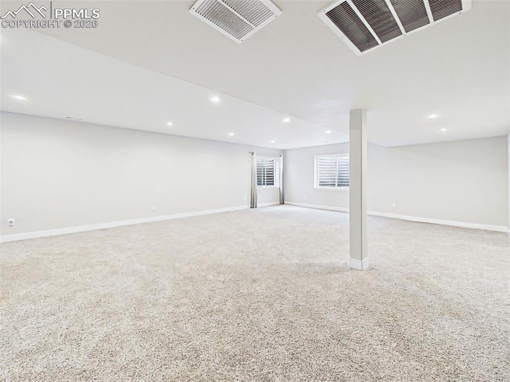 Image 27 of 50: Wide staircase entry leading into a fully finished basement with open-conce