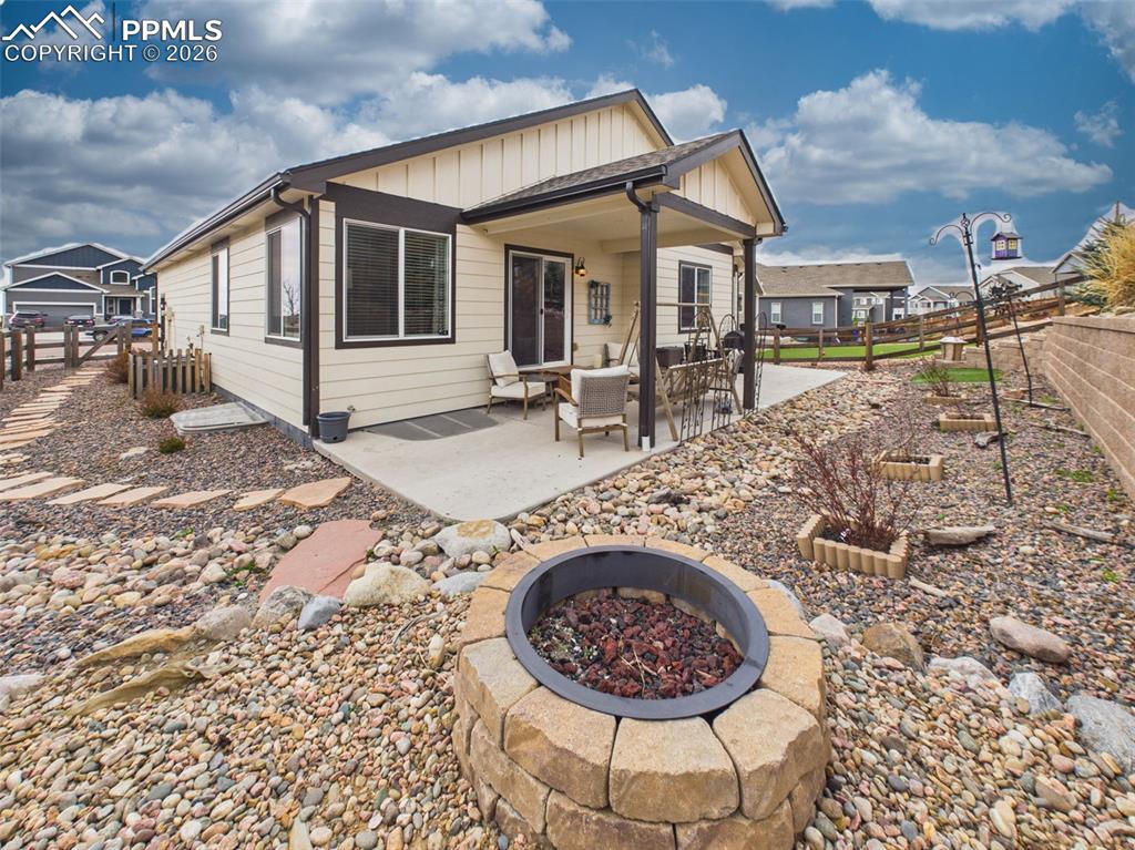 Image 37 of 50: Backyard with fire pit, terraced landscaping, and low-maintenance rock desi