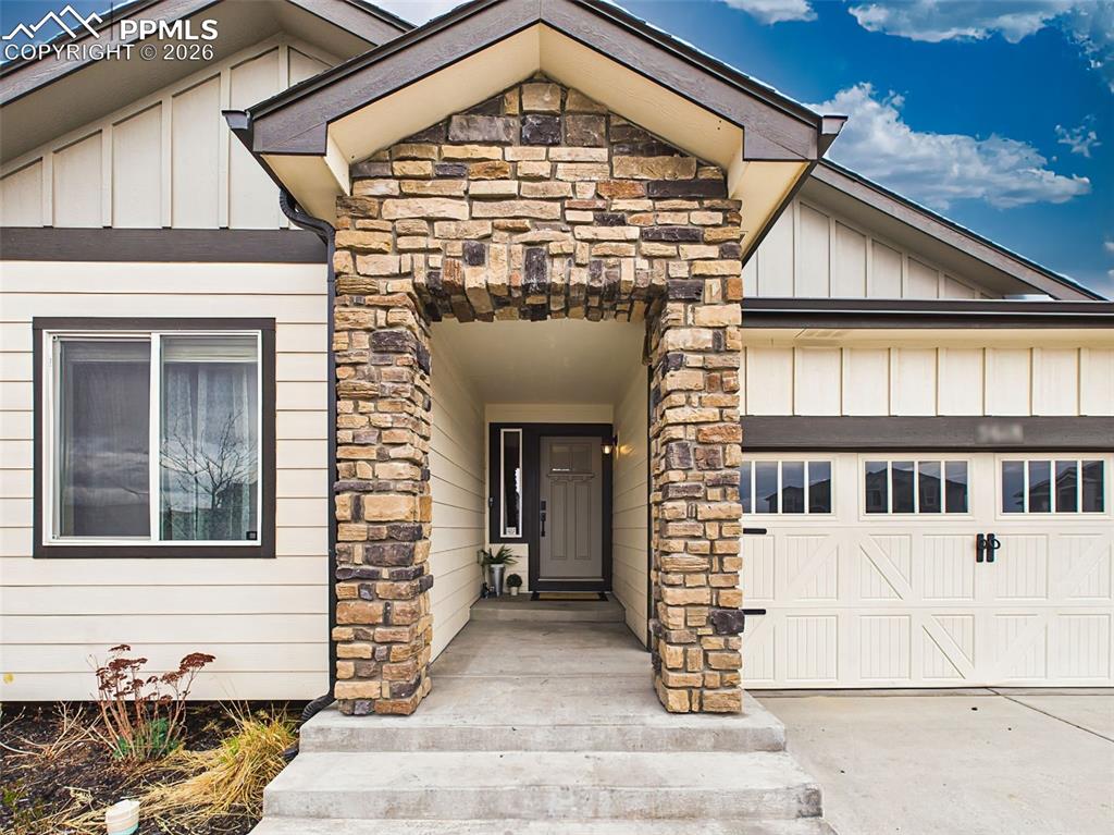 Image 5 of 50: Inviting covered entry with stone columns and sheltered front door approach