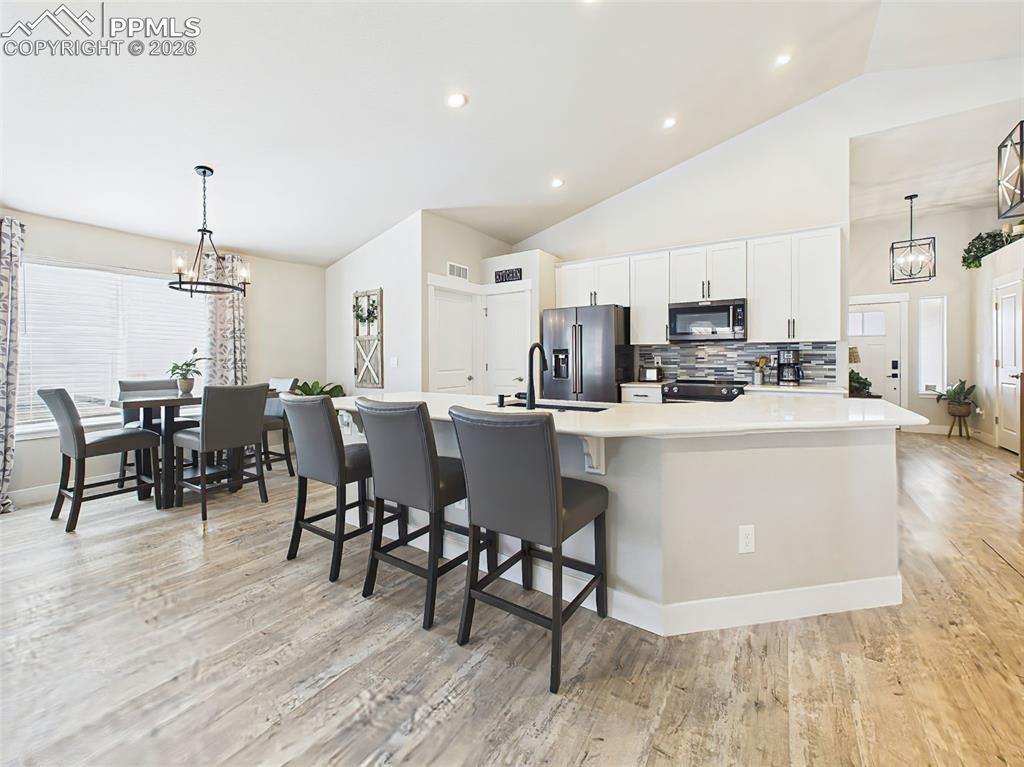 Image 9 of 50: Kitchen and dining area with large island seating, pendant lighting, and am