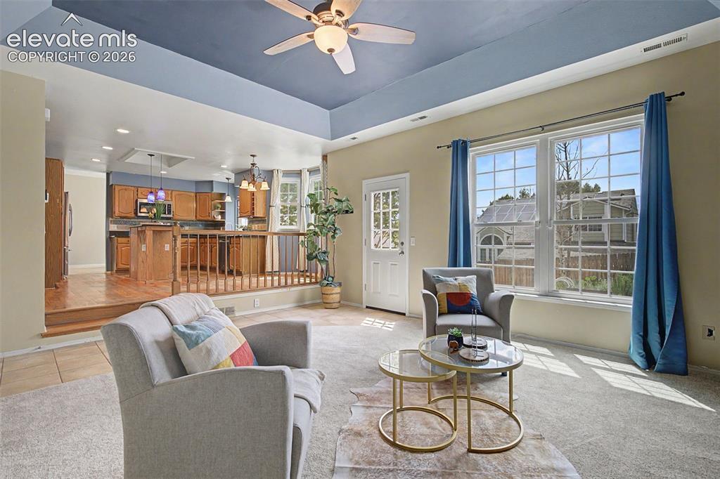 Image 10 of 42: Living area featuring a tray ceiling with a ceiling fan, carpet flooring, a