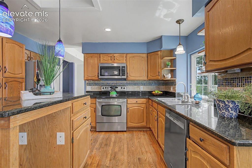 Image 13 of 42: Kitchen featuring wood-finish cabinetry, dark stone countertops, stainless