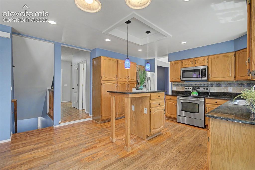 Image 15 of 42: Kitchen featuring wood-finish flooring, wood cabinetry, stainless steel app