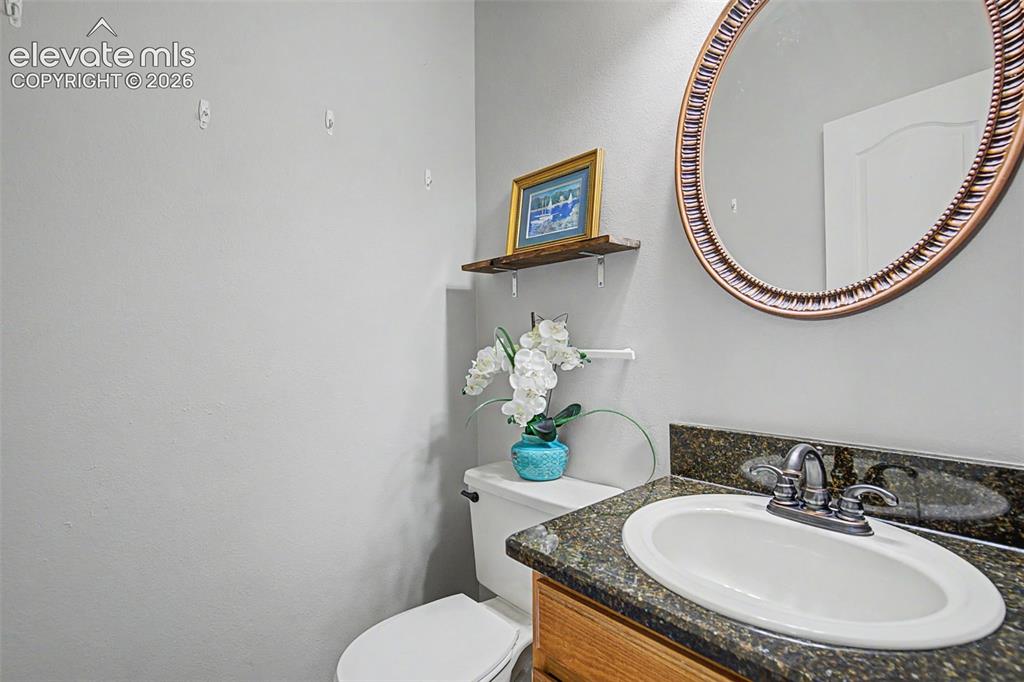 Image 16 of 42: Bathroom featuring a vanity with a dark speckled countertop, an oval underm