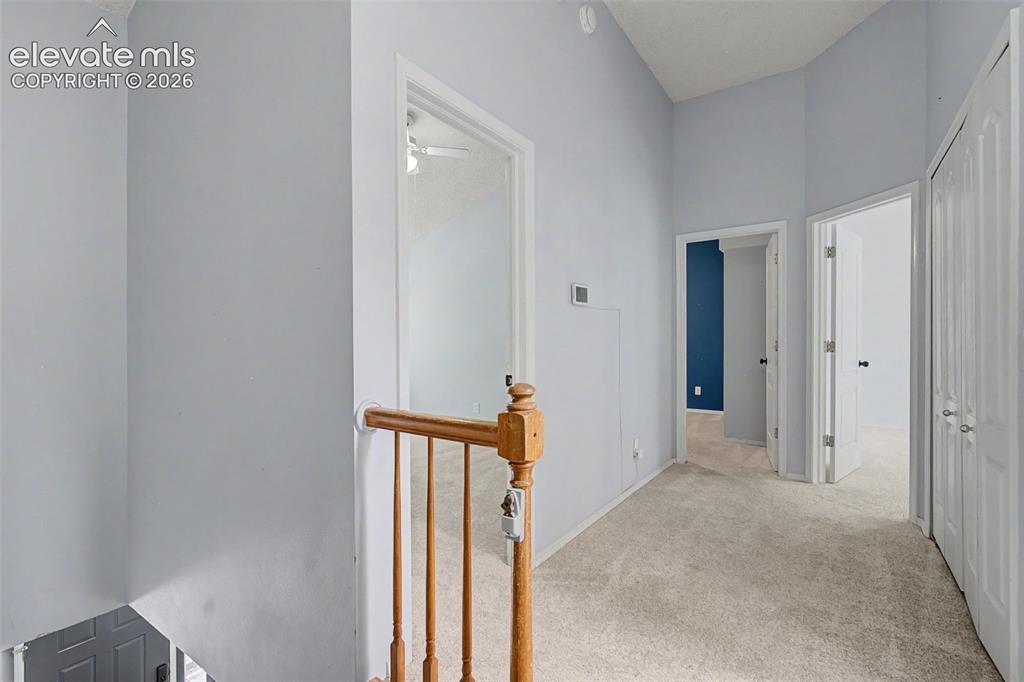 Image 17 of 42: Carpeted hallway featuring a vaulted ceiling, light blue wall paint, multip