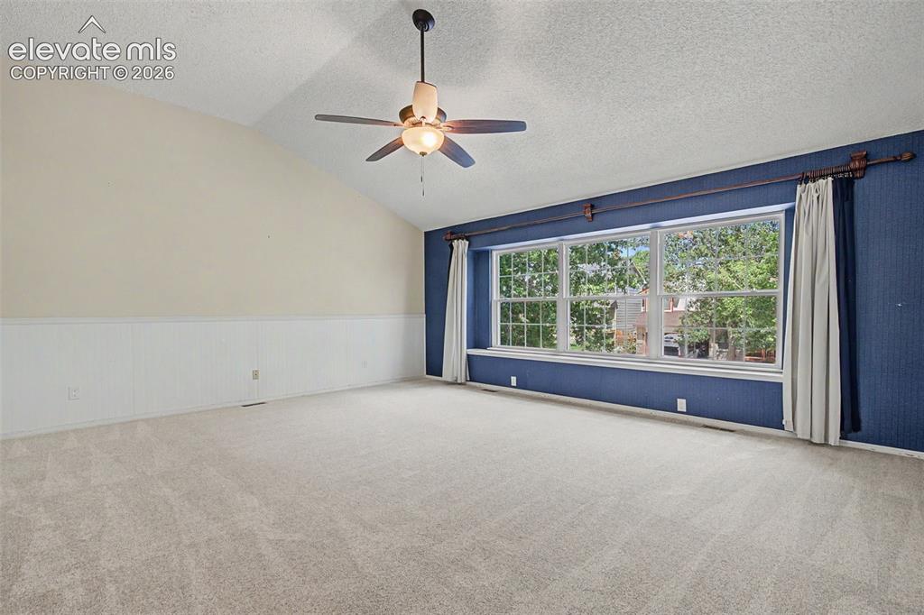 Image 18 of 42: Spacious room featuring vaulted ceilings, a ceiling fan with integrated lig