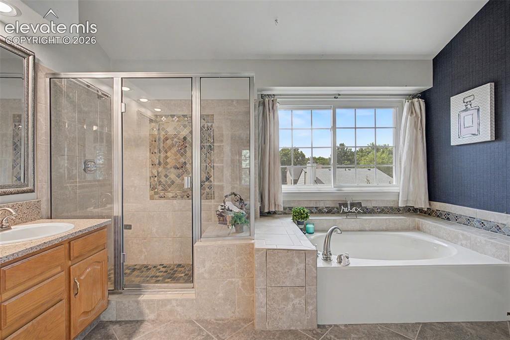 Image 22 of 42: Spacious bathroom featuring a glass-enclosed shower with decorative tile ac