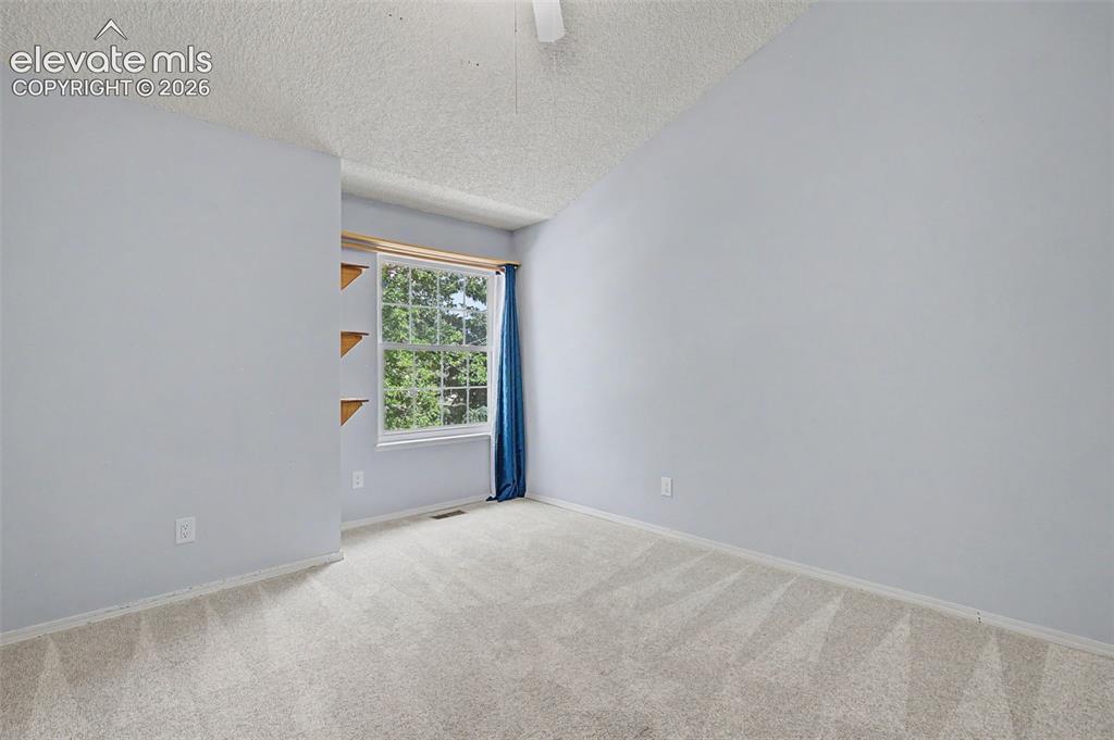 Image 23 of 42: Carpeted room featuring a window with exterior tree views, built-in wooden