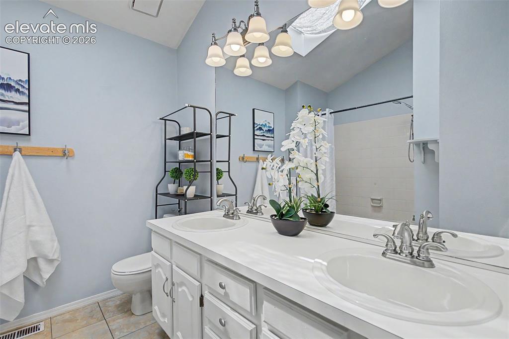 Image 24 of 42: Bathroom featuring a dual vanity with white cabinetry, integrated sinks, an