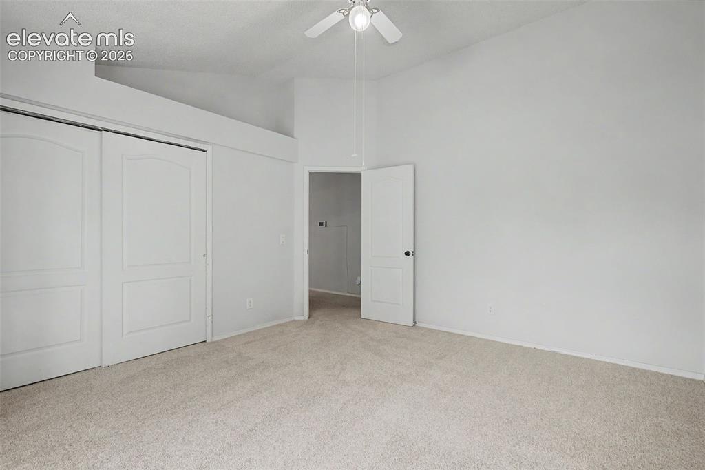 Image 28 of 42: Carpeted room with a vaulted ceiling, ceiling fan, and two-panel sliding cl