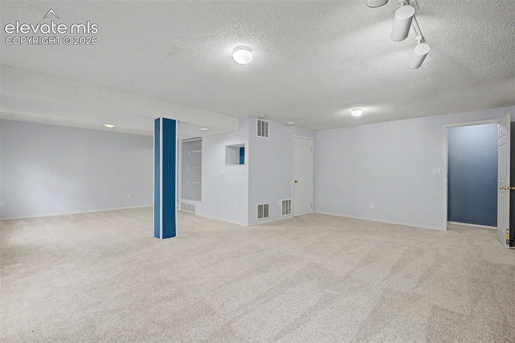 Image 32 of 42: Spacious lower-level room featuring light-toned carpeting and neutral wall