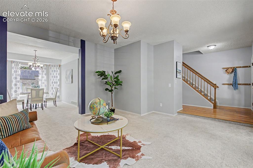 Image 4 of 42: Open concept living area featuring carpeted flooring and a decorative chand