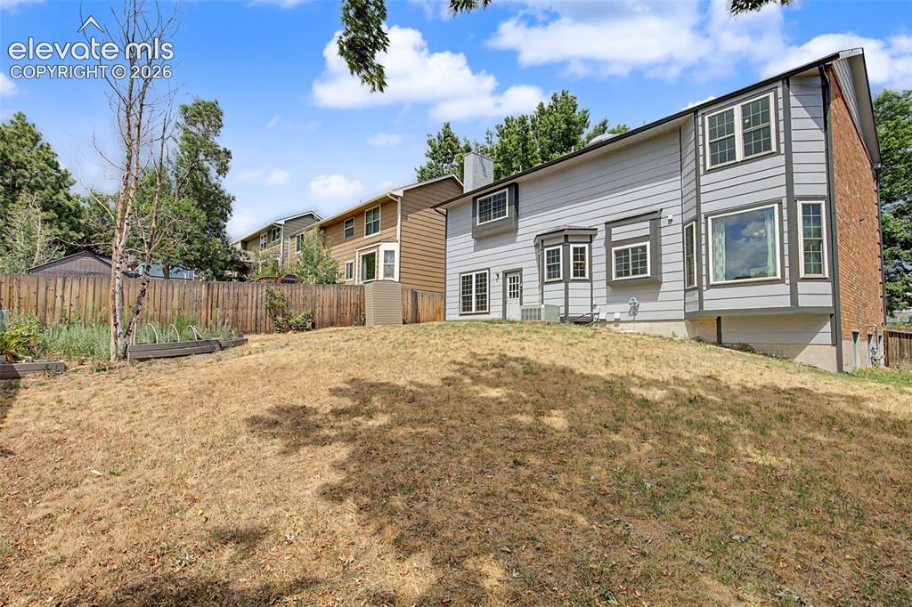 Image 40 of 42: Rear exterior featuring light grey siding with dark grey trim, a brick faca