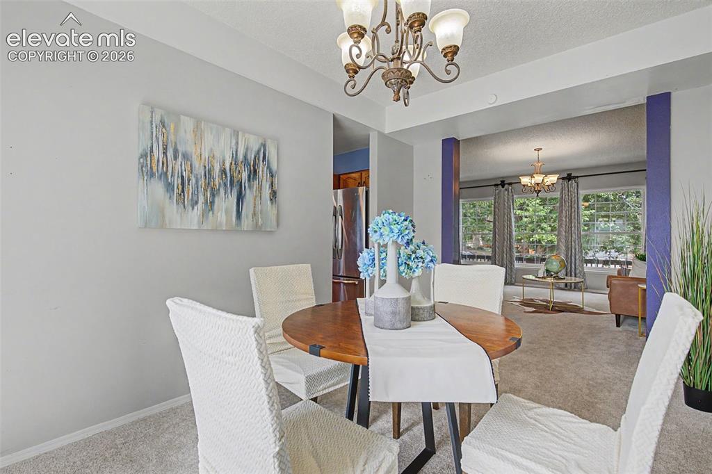 Image 6 of 42: Dining area featuring a bronze chandelier, light gray walls, and carpet flo