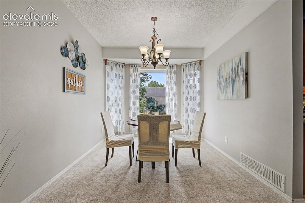 Image 7 of 42: Formal dining area featuring a bay window, a multi-light chandelier, and li